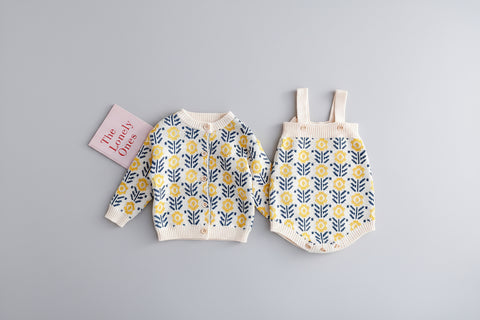 Children's floral-patterned cardigan and overalls on a beige surface with 'Love Lovely Ones' sign.