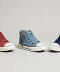 Three high-top sneakers in red, blue, and navy on a beige surface.
