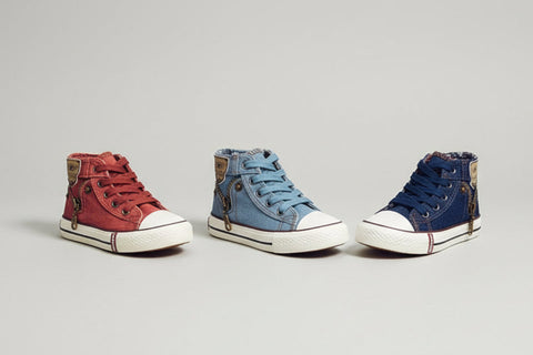 Three high-top sneakers in red, blue, and navy on a beige surface.