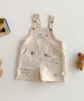 Beige children's overalls with embroidered designs on a light gray background