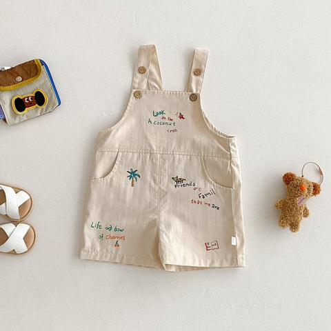 Beige children's overalls with embroidered designs on a light gray background