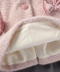 Close-up of a hand holding a pink and white textured fabric with floral details.