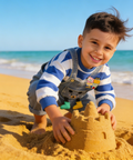 Child building a sandcastle on a beach with ocean in the background