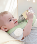Baby holding a green and white bottle with a textured surface