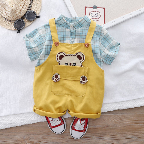 Yellow romper with bear design and plaid shirt on a white surface