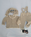 Knitted baby outfit with cardigan, pants, and scarf on a light gray background