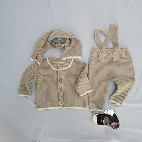 Knitted baby outfit with cardigan, pants, and scarf on a light gray background