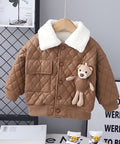 Brown quilted jacket with teddy bear patch on a hanger against a gray wall.