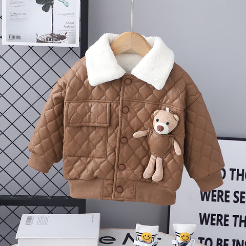 Brown quilted jacket with teddy bear patch on a hanger against a gray wall.