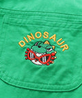 Green fabric with a dinosaur embroidered design and a red tag on a light blue background.