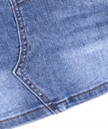 Close-up of a blue denim fabric with a slight tear on a white background