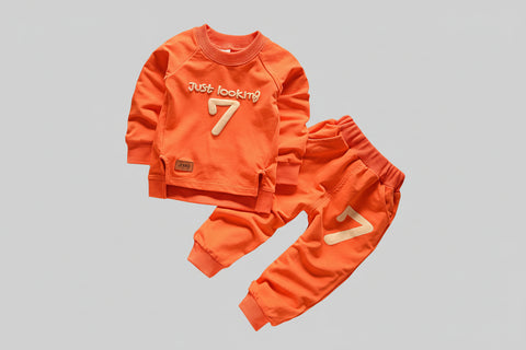 Orange children's outfit with 'Just looking 7' text on a textured surface