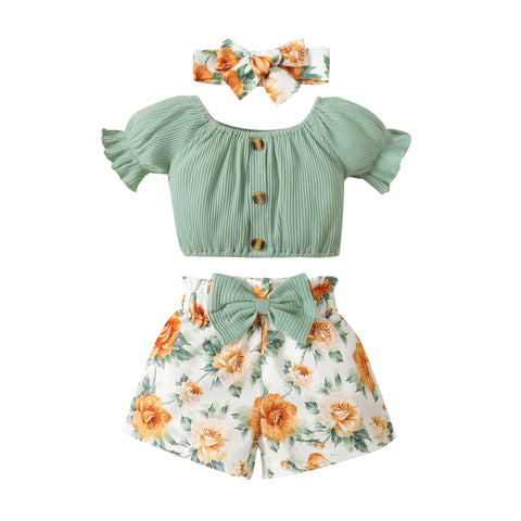 Baby outfit set with green top, floral shorts, and matching headband on a white background