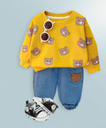 Yellow sweater with bear patterns, blue jeans, and black sneakers on a light blue background
