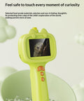 Green toy with screen displaying an owl, placed on a green surface with water droplets.