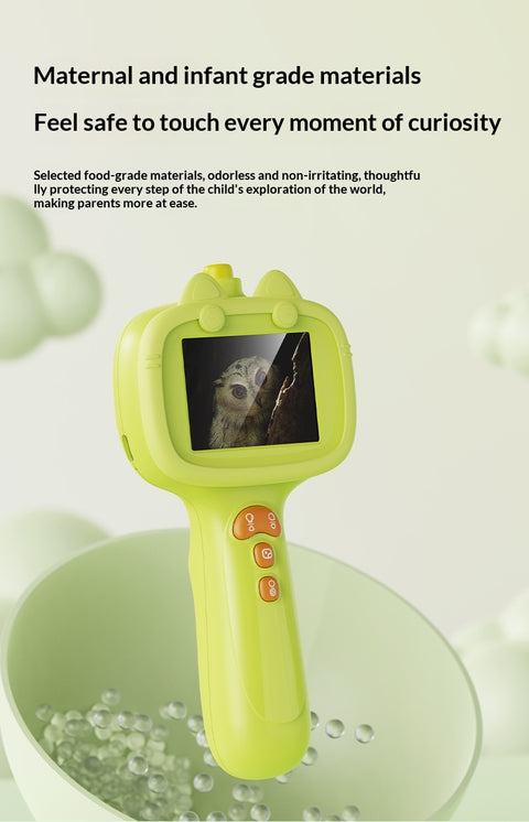 Green toy with screen displaying an owl, placed on a green surface with water droplets.