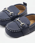 Pair of navy blue baby shoes with gold buckles on a white background