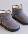 Pair of gray children's boots with fur lining on a beige surface