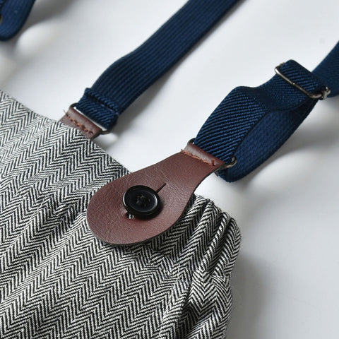 Close-up of a textured bag with a blue strap and brown leather patch on a white background