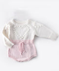 White and pink baby outfit on a red background