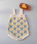 Knitted baby romper with floral pattern on a white surface