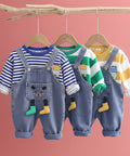 Three children's outfits with denim overalls and colorful shirts on hangers against a light gray background.