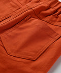 Close-up of an orange pocket on a garment with a light gray background