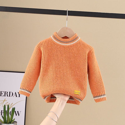 Orange sweater on a hanger against a beige wall with a plant and framed picture in the background.