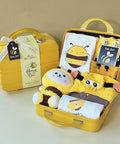 Yellow baby gift set with bee-themed items in an open suitcase on a beige background