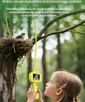 Child observing a bird's nest with a camera attached to a tree branch, surrounded by nature.