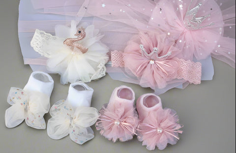 Collection of baby girl accessories including shoes, headband, and dress on a light gray background.