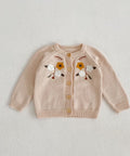 Beige cardigan with floral embroidery on a light gray background