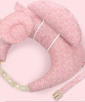 Pink baby support pillow with straps on a light pink background