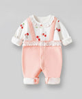 Baby outfit with white top and pink pants on a gray background