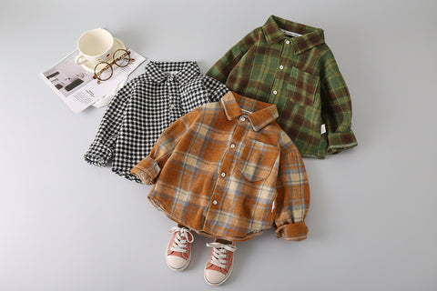 Three plaid shirts in different colors on a white surface with a cup and glasses in the background.