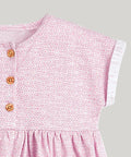 Close-up of a pink dress with a geometric pattern and buttons on a white background