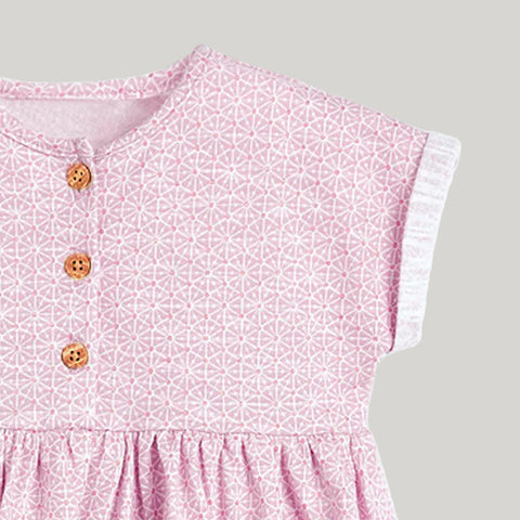 Close-up of a pink dress with a geometric pattern and buttons on a white background