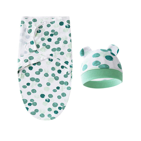 Baby swaddle and hat set with green polka dot pattern on a white background