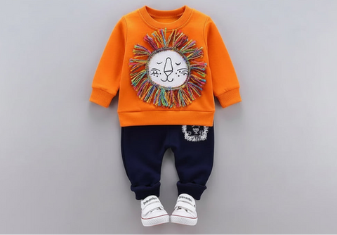 Children's outfit with orange sweatshirt and navy pants on a gray background