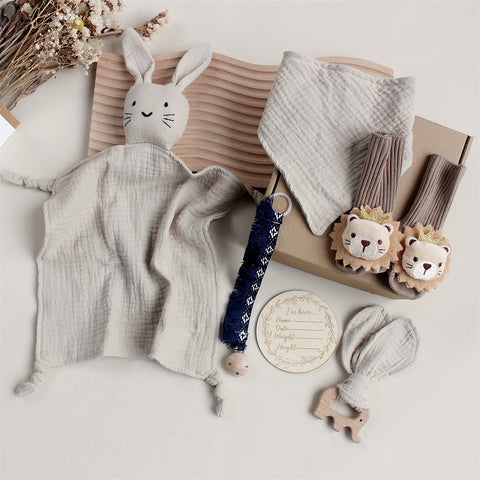 Collection of baby items including a plush bunny, blanket, and toys on a light surface.