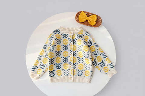 Knitted cardigan with yellow floral pattern on a white surface