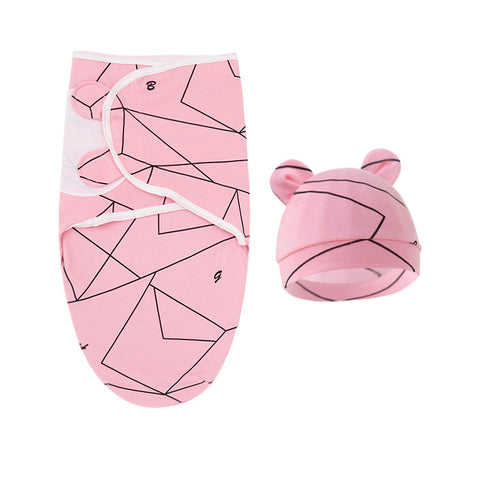 Pink baby swaddle with geometric pattern and matching hat on a white background