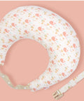 Nursing pillow with floral pattern and strap on a pink background