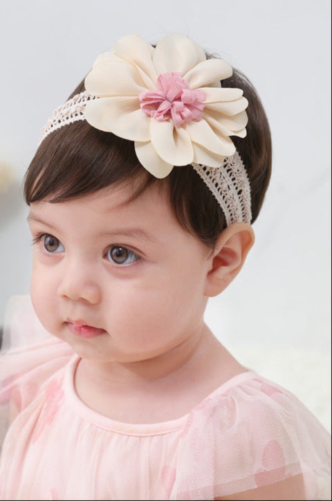 Child wearing a decorative headband with a large flower on a plain background