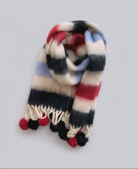 Colorful striped scarf with pom-pom ends on a light gray background