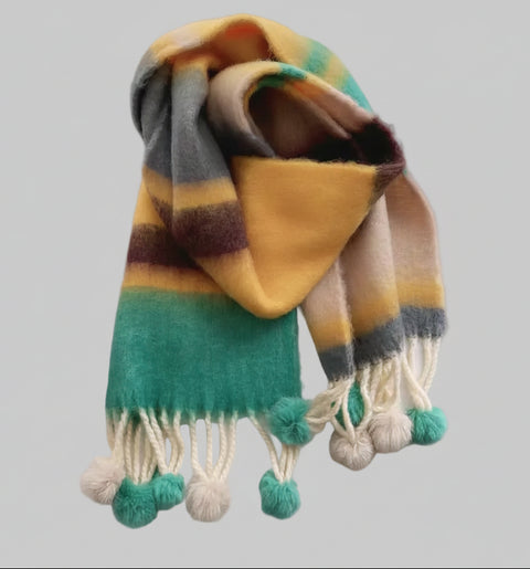 Colorful striped scarf with pom-poms on a light gray background