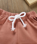 Close-up of pink pants with a white drawstring on a wooden surface