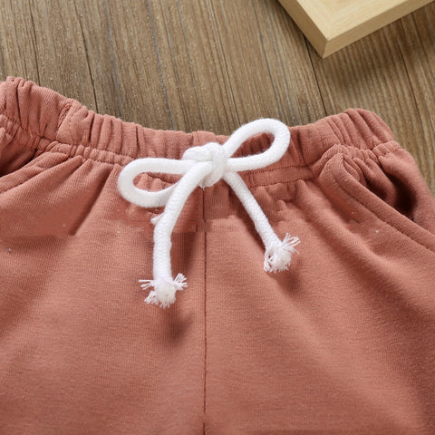 Close-up of pink pants with a white drawstring on a wooden surface