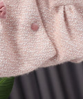 Close-up of a textured pink fabric with a hand holding it against a dark background