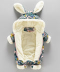 Floral-patterned baby bouncer with bunny ears on a gray background